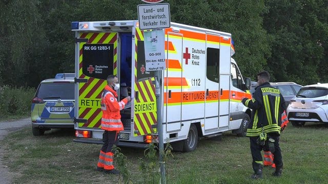 Rettungskräfte stehen am Ufer des Rheins bei Trebur.