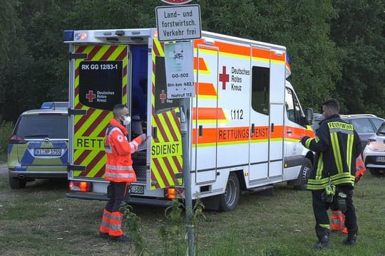 Rettungskräfte stehen am Ufer des Rheins bei Trebur.