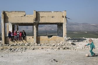 Kinder spielen in den Trümmern einer zerstörten Schule.