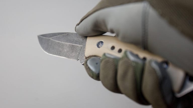 Eine Hand hält ein Messer: In Berlin-Mitte ist ein Mann überfallen worden.