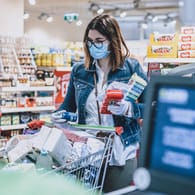 Eine Frau beim Einkaufen in Corona-Zeiten (Symbolbild): Für Kunden könnte es in den nächsten Monaten etwas günstiger werden.