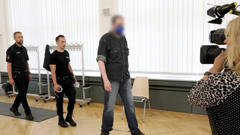 Justizmitarbeiter führen den 39-Jährigen in den Saal des Rostocker Landgerichts.