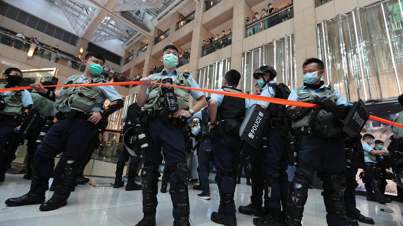 Polizisten in einem Einkaufszentrum in Hongkong: Erste Festnahme unter dem neuen Gesetz, das Demokratie-Aktivisten kleinhalten soll.