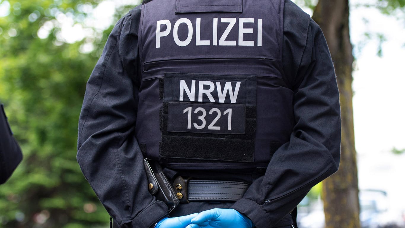 Ein Polizist mit Gummihandschuhen verkreutzt die Hände auf dem Rücken (Symbolbild): In Hagen hat ein Mann seine Ehefrau mit dem Messer bedroht.