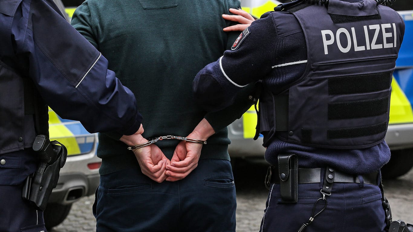 Zwei Polizisten mit einer Person in Handschellen (Symbolbild): In Wolfsburg ist ein mutmaßlicher Mafiosi geschnappt worden.