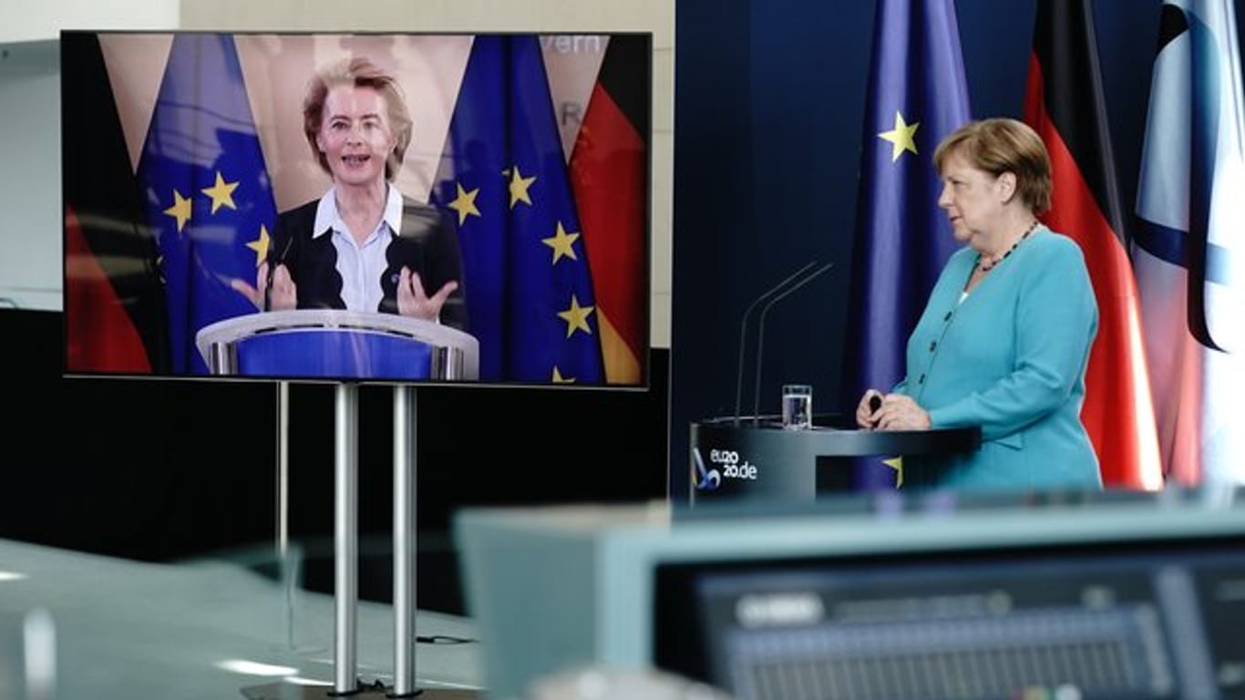 Bundeskanzlerin Angela Merkel (CDU) hört im Foyer des Bundeskanzleramtes EU-Kommissionspräsidentin Ursula von der Leyen (CDU), die per Video zugeschaltet ist, zu.