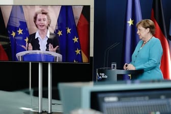 Bundeskanzlerin Angela Merkel (CDU) hört im Foyer des Bundeskanzleramtes EU-Kommissionspräsidentin Ursula von der Leyen (CDU), die per Video zugeschaltet ist, zu.