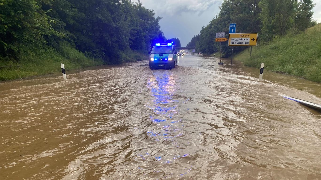 Ein Polizeiwagen im Einsatz auf der B318 bei Holzkirchen: Das Wasser stand dort bis zu einem Meter hoch.