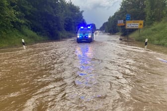 Ein Polizeiwagen im Einsatz auf der B318 bei Holzkirchen: Das Wasser stand dort bis zu einem Meter hoch.