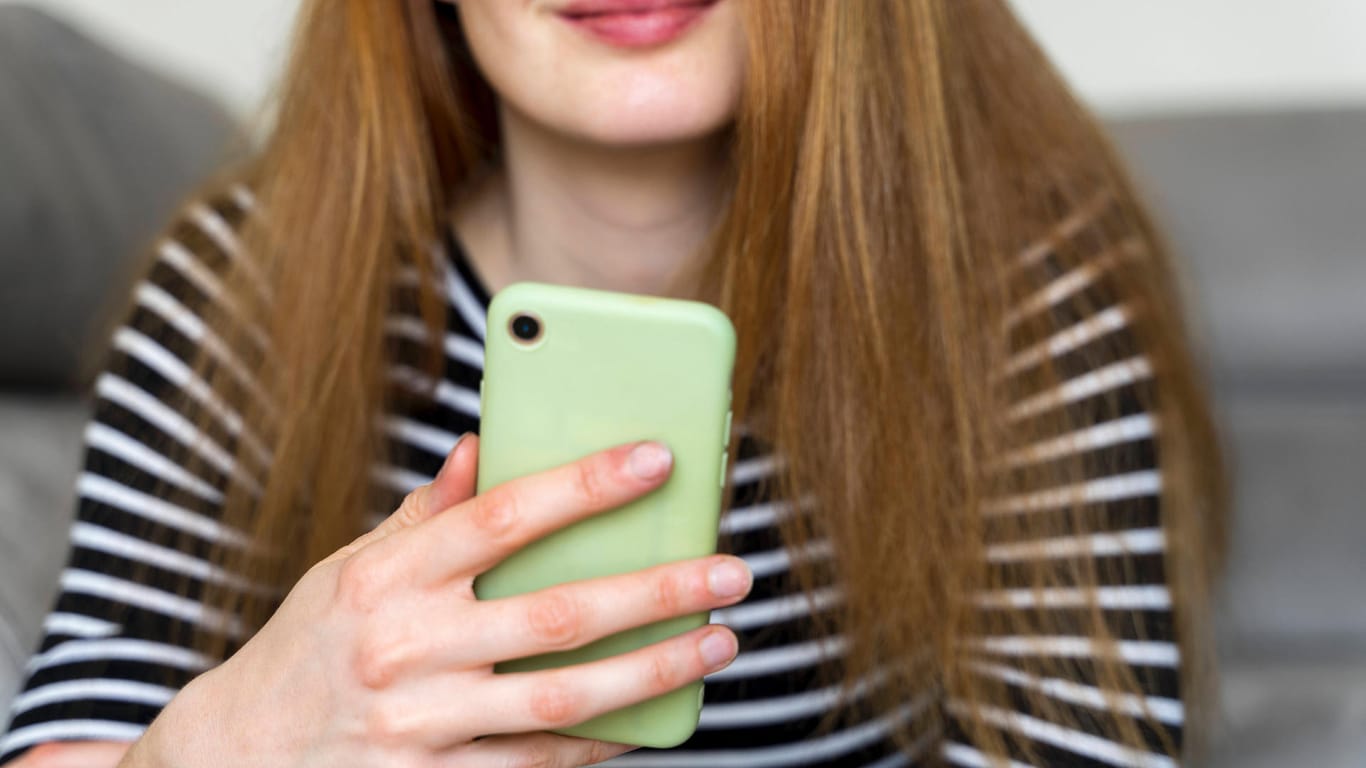 Eine Frau mit Smartphone (Symbolbild): Mit bestimmten Codes können Sie auf Ihrem Handy versteckte Funktionen aktivieren.