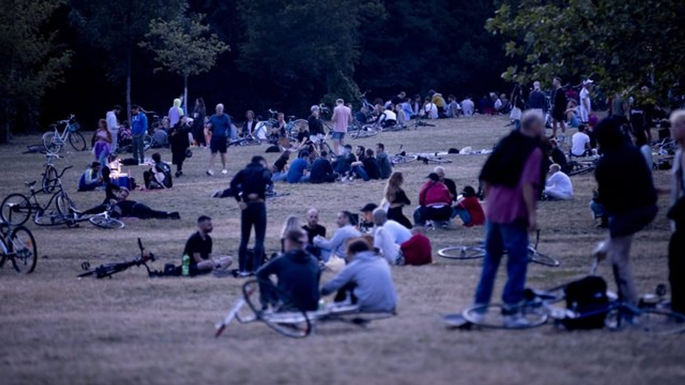 Menschen sitzen nachts im Volkspark Hasenheide in Berlin auf einer Wiese: Dort treffen sich besonders am Wochenende viele Menschen, teilweise um zu Feiern.