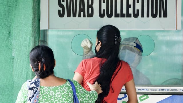 Von einer Frau im indischen Guwahati wird ein Nasenabstrich an einer Entnahmestelle genommen.