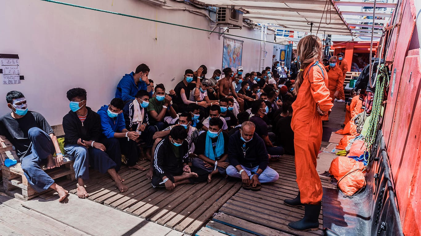 Migranten sitzen an Deck des Rettungsschiffs "Ocean Viking": Italien hat die Menschen an Bord auf das Coronavirus testen lassen – und plant ihre Übernahme auf ein Quarantäneschiff.