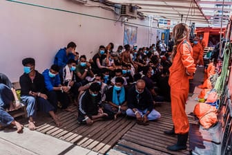 Migranten sitzen an Deck des Rettungsschiffs "Ocean Viking": Italien hat die Menschen an Bord auf das Coronavirus testen lassen – und plant ihre Übernahme auf ein Quarantäneschiff.