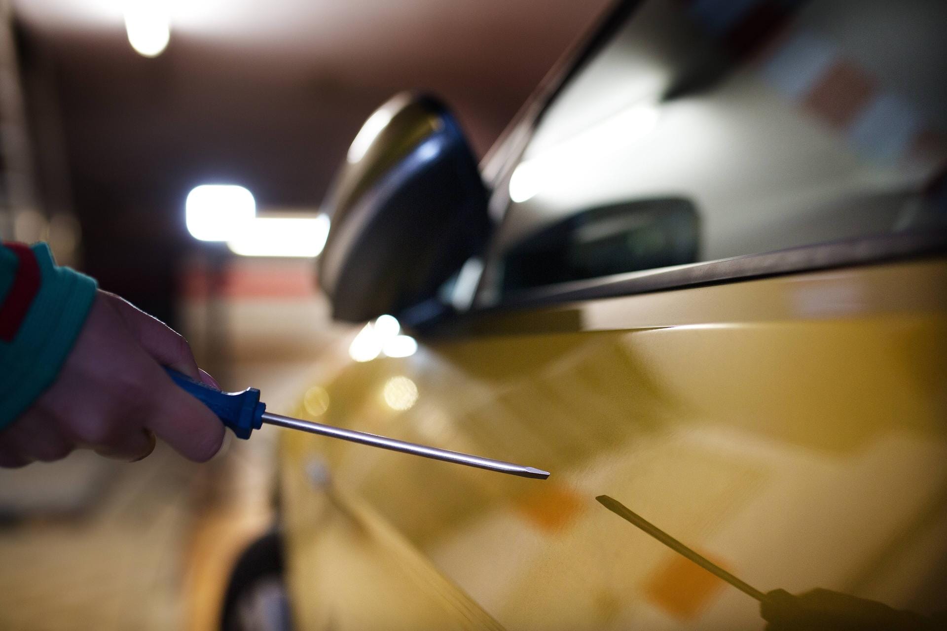 Eine Person zerkratzt mit einem Schraubenzieher ein Auto (Symbolbild): In Braunschweig wurden Dutzende Autos beschädigt.