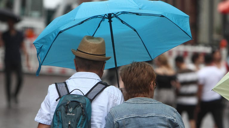 Paar geht während eines Regenschauers mit Regenschirm in der Innenstadt von Heidelberg, Baden Württemberg, Deutschland *