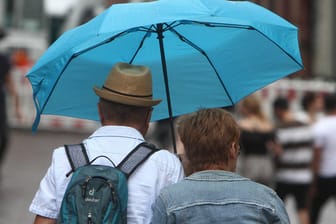 Paar geht während eines Regenschauers mit Regenschirm in der Innenstadt von Heidelberg, Baden Württemberg, Deutschland *