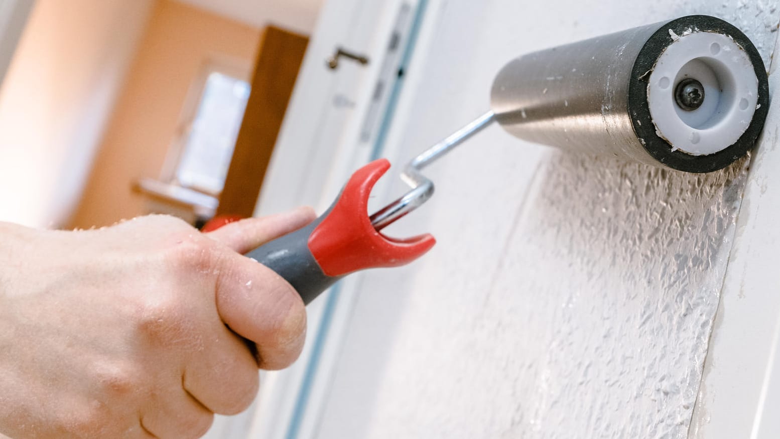 Ein Mann streicht mit einer Rolle über eine Tapete (Symbolbild): Mieter dürfen ihre Vermieter zum Renovieren verpflichten – müssen aber die Kosten mittragen.