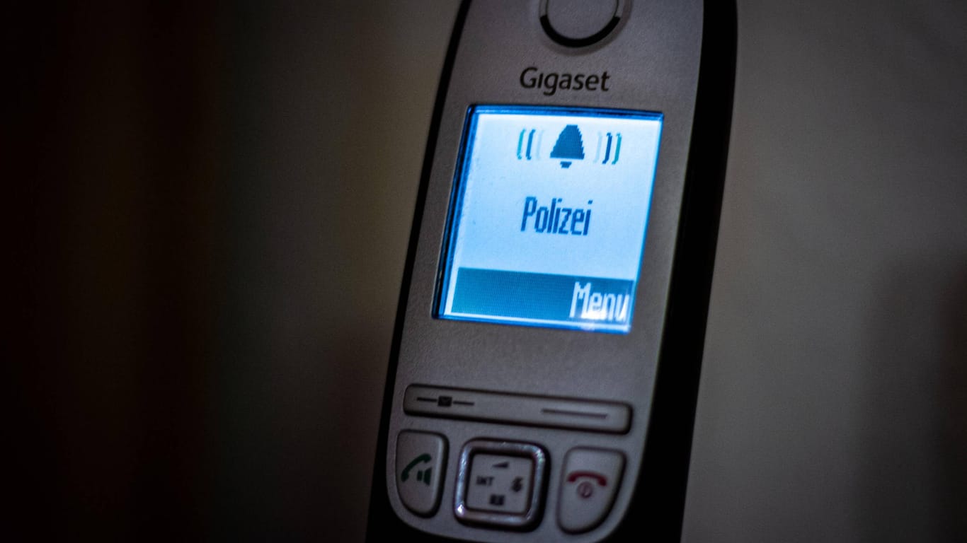 Das Wort "Polizei" leuchtet auf einem Telefon auf (Symboldbild): In München hat eine Frau ihr Millionen teures Haus durch Betrüger verloren.