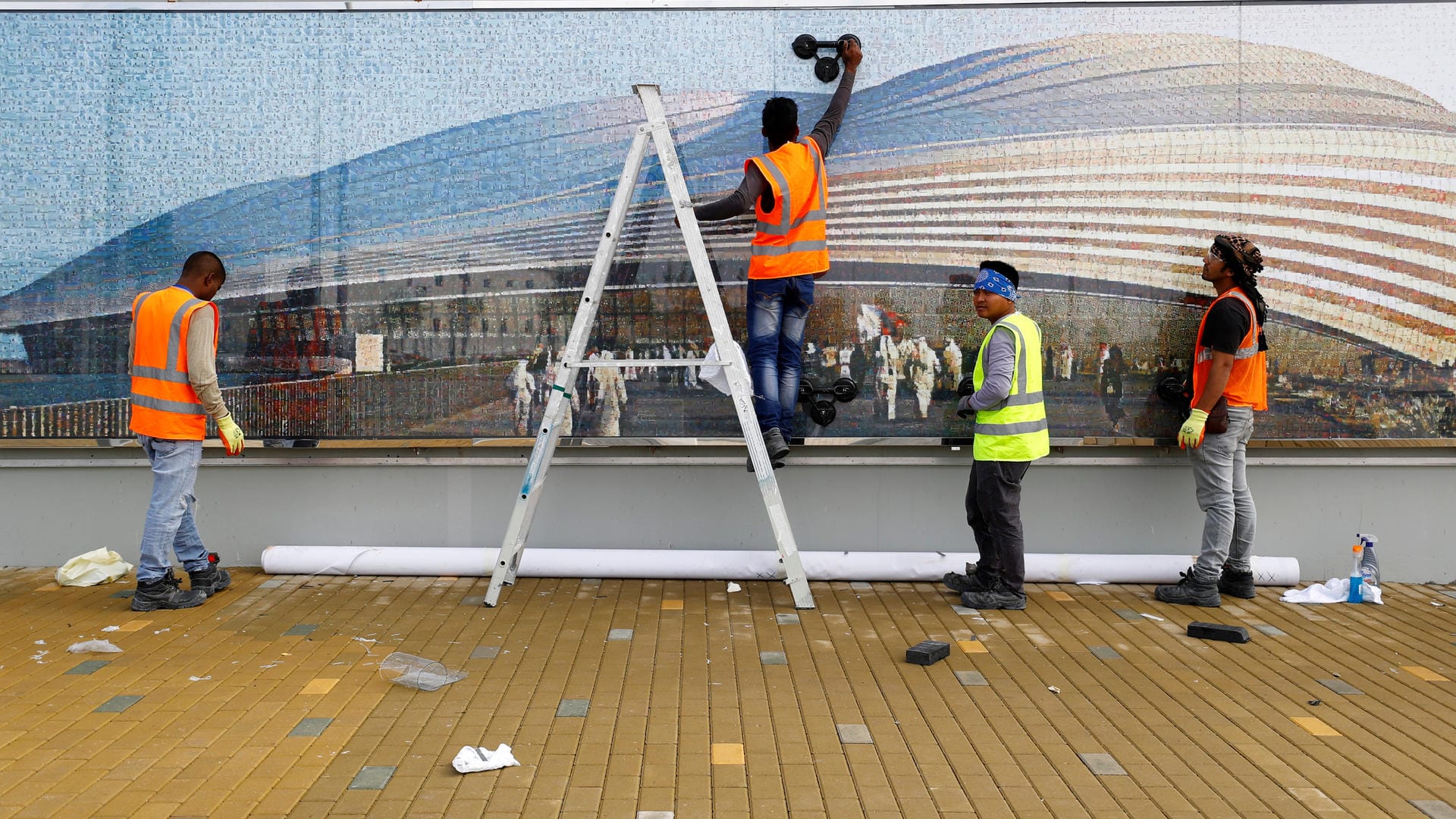 Arbeiter vor einem Poster des WM-Stadions in Al Wakrah.