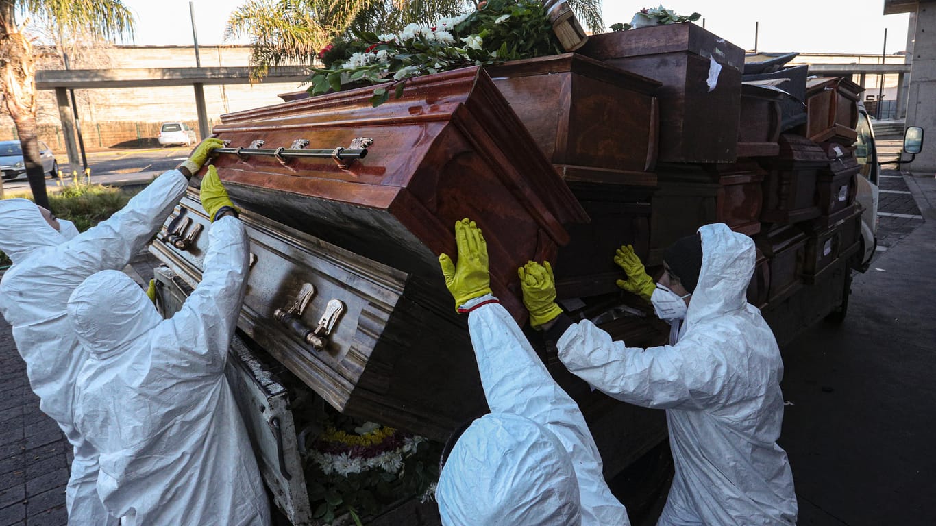 Arbeiter in Schutzanzügen stapeln in Santiago de Chile Särge, in denen zuvor noch Covid-19-Tote zu einem Krematorium gebracht wurden.