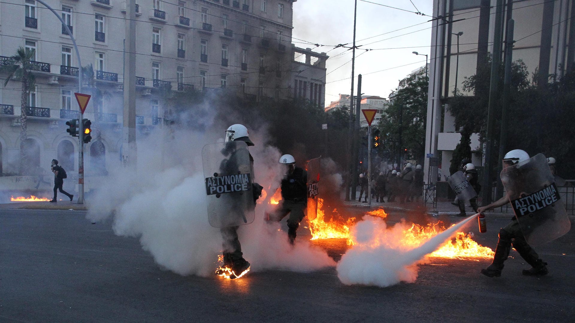 Proteste in Griechenland: Bereitschaftspolizisten versuchen vor dem griechischen Parlament Flammen auszuweichen, während einer Demonstration gegen das neue Protestgesetz.