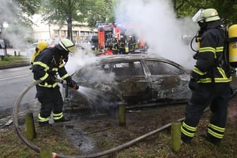 Feuerwehrleute löschen während des G20-Gipfels im Jahr 2017 ein brennendes Auto in Hamburg-Altona.