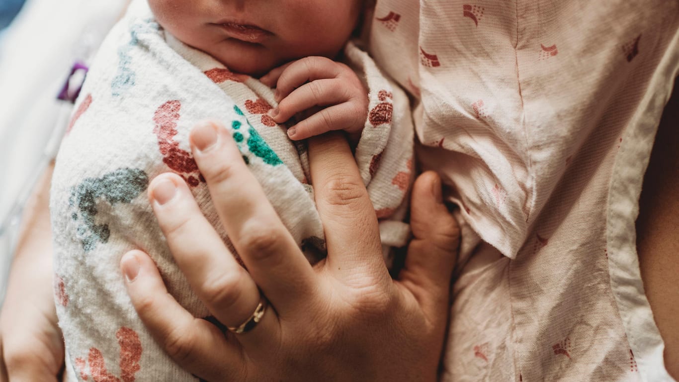 Eine Mutter hält ihr Neugeborenes in der Hand (Symbolbild): In Bielefeld ist es zu einer seltenen Geburt gekommen.