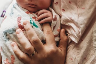 Eine Mutter hält ihr Neugeborenes in der Hand (Symbolbild): In Bielefeld ist es zu einer seltenen Geburt gekommen.