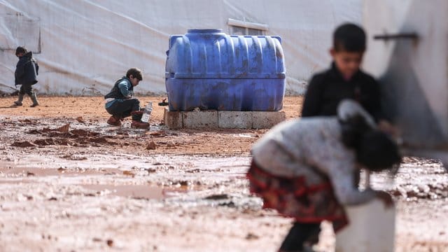 Kinder füllen in einem provisorischen Lager in der Region Idlib Behälter mit Wasser auf.