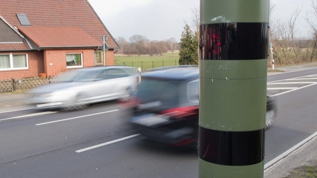 Autos fahren an einem Blitzgerät zur Geschwindigkeitskontrolle vorbei.