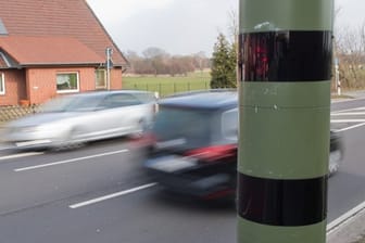 Autos fahren an einem Blitzgerät zur Geschwindigkeitskontrolle vorbei.