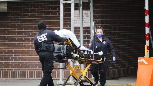 Mitarbeiter des Gesundheitswesens schieben einen Patienten in das Brooklyn Hospital Center in Brooklyn. Mitarbeiter des Gesundheitswesens schieben einen Patienten in das Brooklyn Hospital Center in Brooklyn.