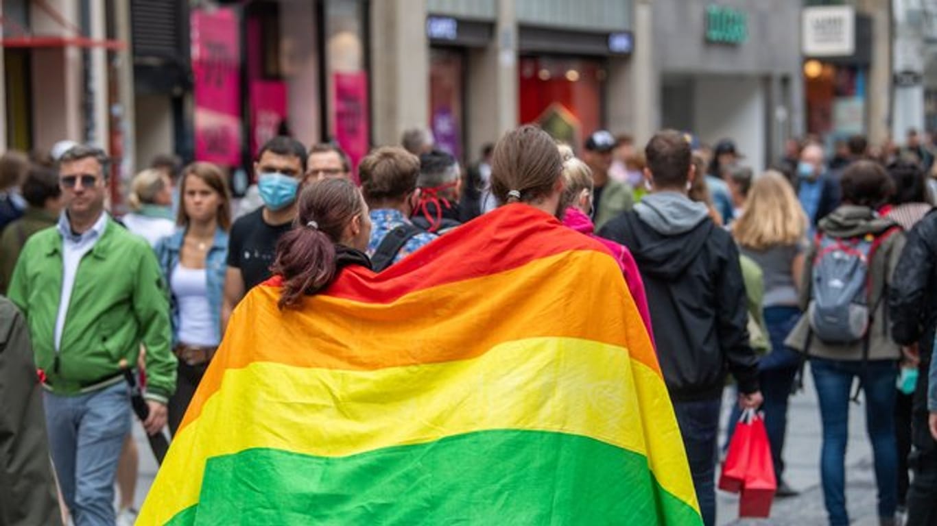 Zwei Frauen laufen umhüllt von einer Pride-Flagge durch die Münchner Innenstadt.
