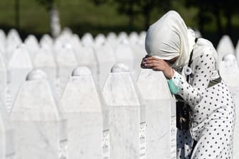 Eine Frau trauert auf dem Friedhof der Gedenkstätte Potocari in der Nähe von Srebrenica an einem Grab.