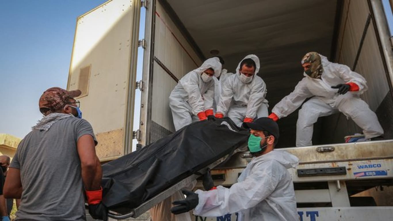 Arbeiter in Schutzkleidung beladen in Bagdad einen Kühlwagen mit Leichen von Menschen, die am Coronavirus gestorben sind.