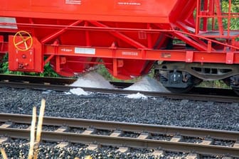 Weißes Pulver aus einem Waggon eines Güterzuges ist im Gleisbett zu sehen.