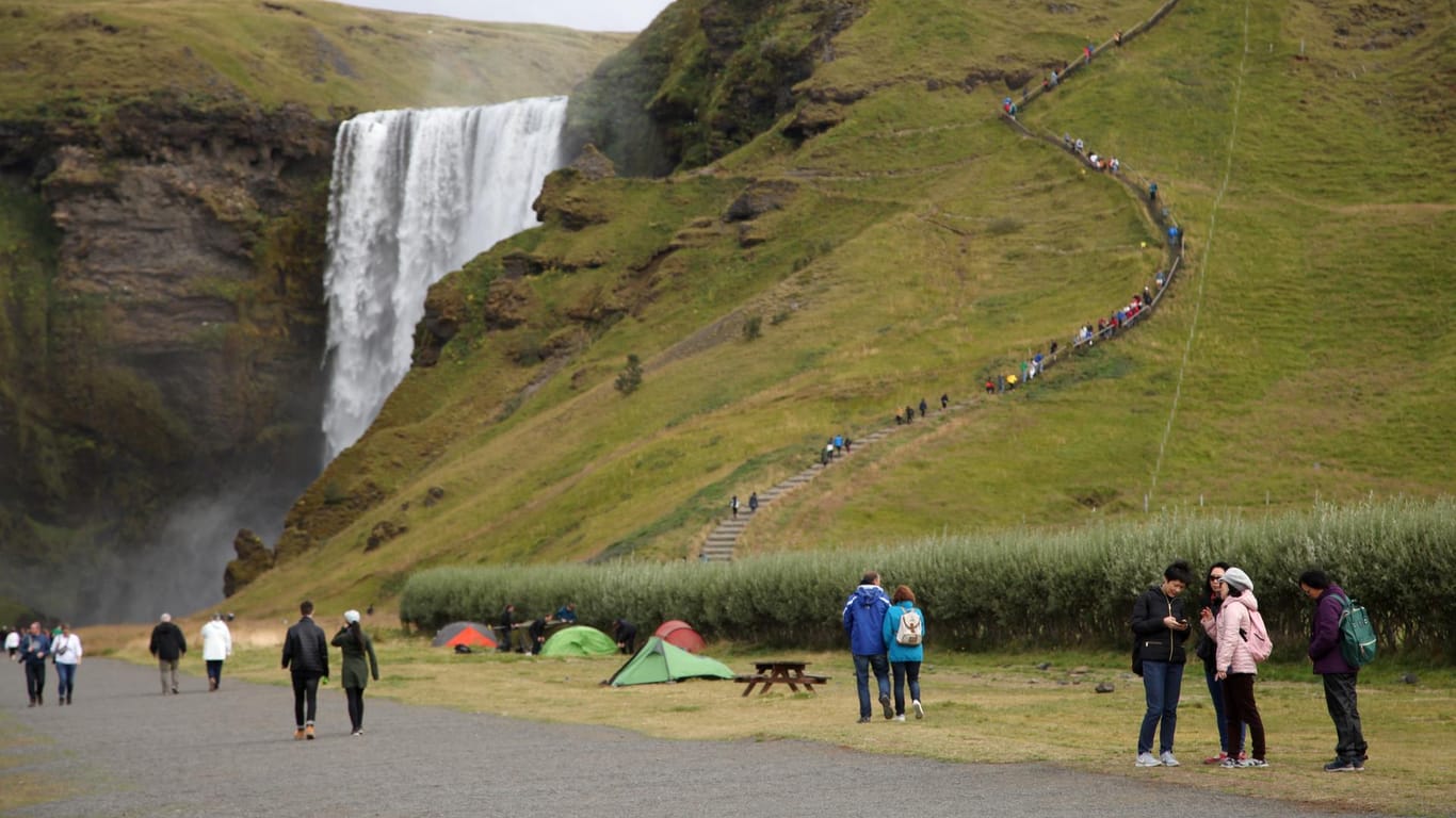 Touristen spazieren am Wasserfall Skogafoss vorbei: Viel Land, wenig Leute, so sieht es momentan auf Island aus.