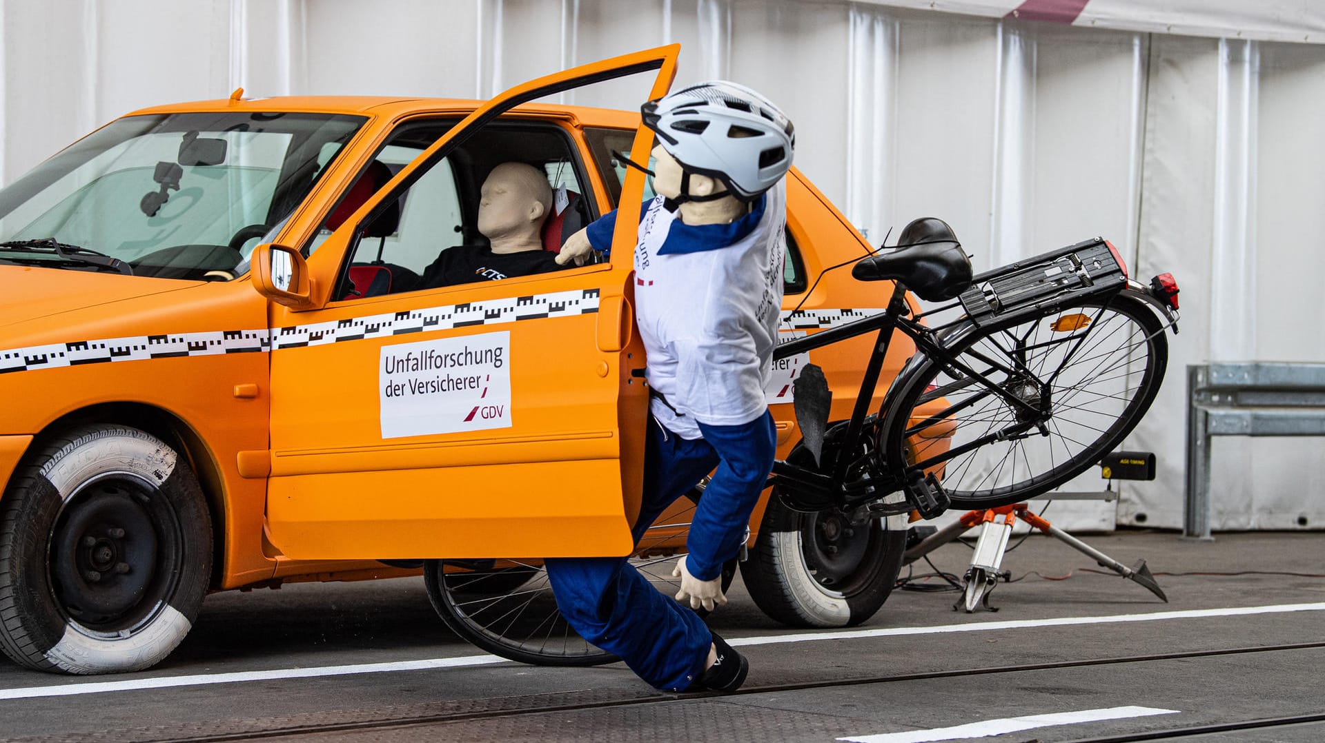 "Dooring"-Unfall: Bei einem Crashtest der Unfallforscher der Versicherer fährt ein Crashtest-Dummy auf einem Fahrrad gegen eine geöffnete Tür eines geparkten Autos.