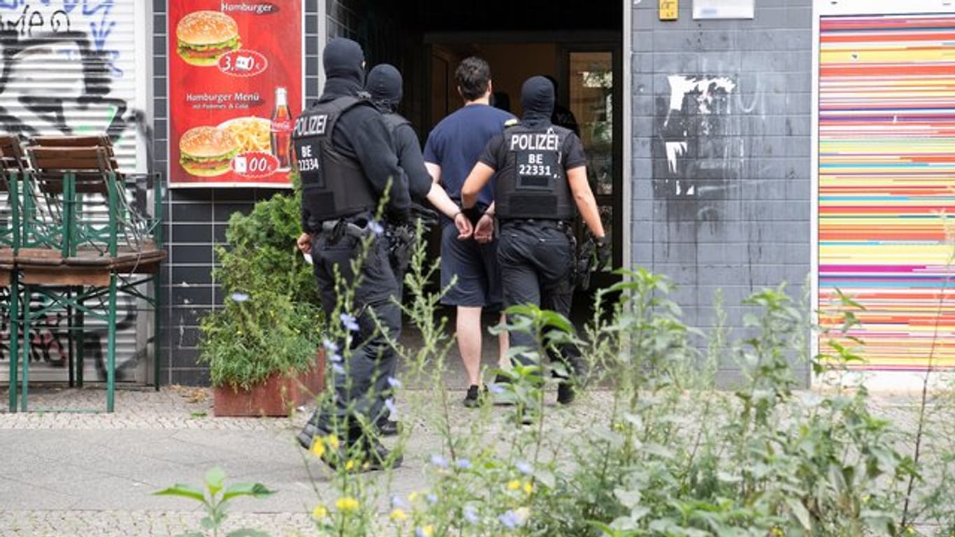 Polizeibeamte führen einen mit Handschellen gefesselten Mann in ein Haus in Berlin-Kreuzberg.