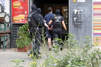 Polizeibeamte führen einen mit Handschellen gefesselten Mann in ein Haus in Berlin-Kreuzberg.