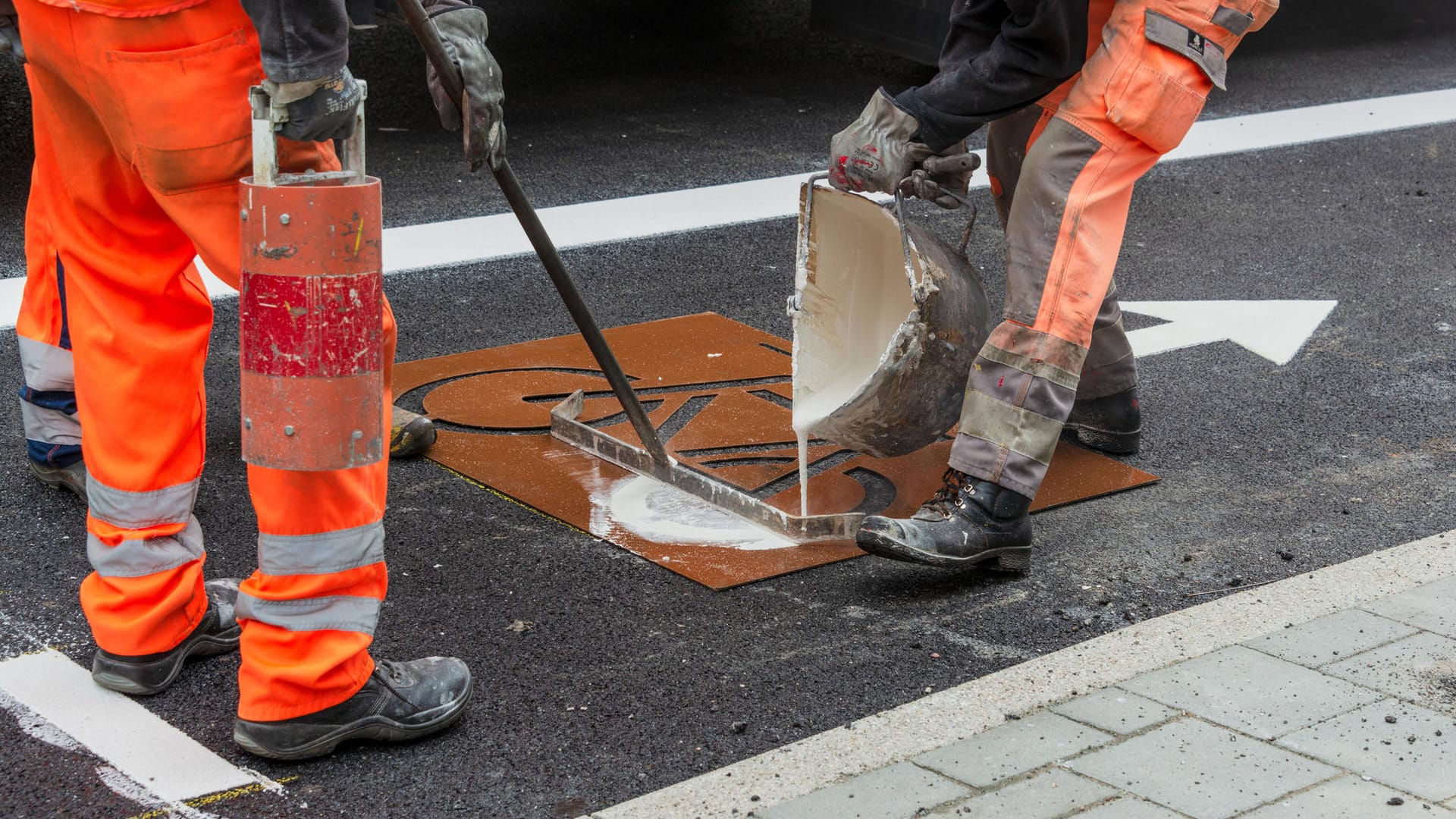 Fahrbahnmarkierungen werden auf den neuen Belag einer Straße angebracht (Symbolbild): In Wolfsburg sollen die Bürger bald nicht mehr direkt für den Straßenausbau Beiträge bezahlen.