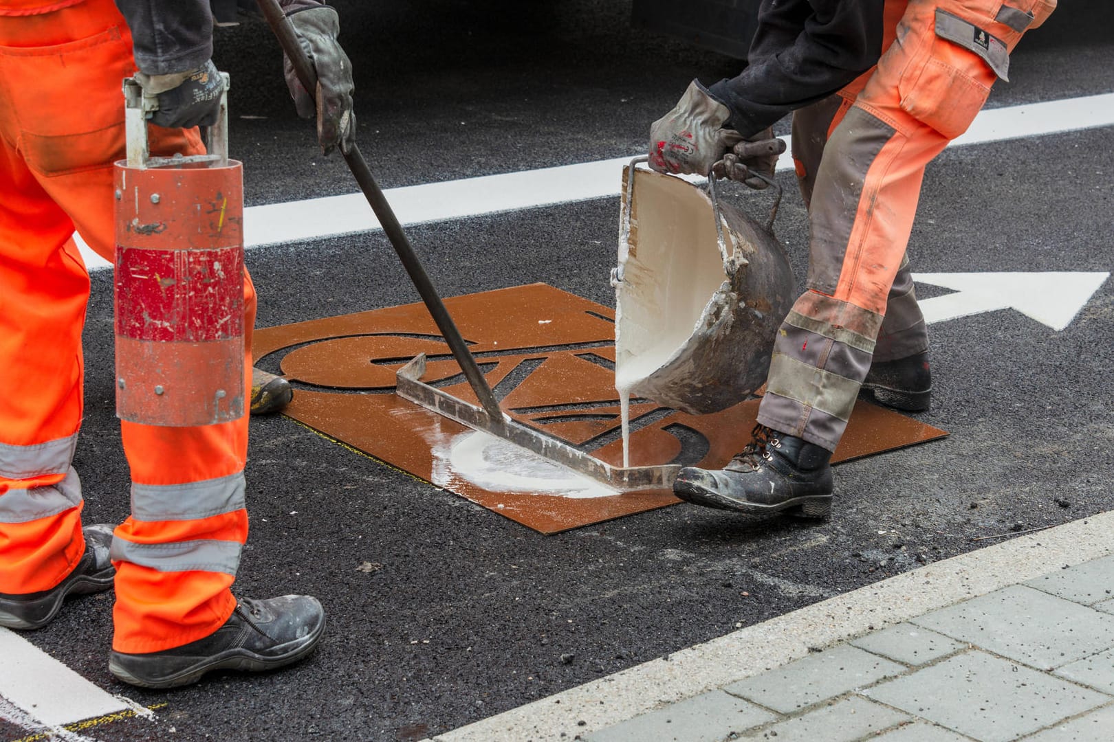 Fahrbahnmarkierungen werden auf den neuen Belag einer Straße angebracht (Symbolbild): In Wolfsburg sollen die Bürger bald nicht mehr direkt für den Straßenausbau Beiträge bezahlen.