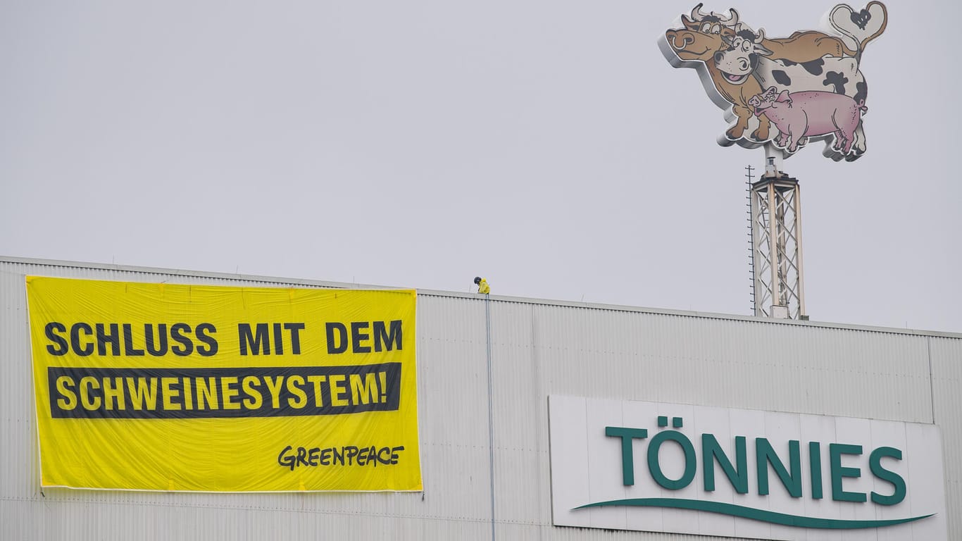 Zwei Greenpeace-Aktivisten landeten mit ihren Gleitschirmen auf dem Dach des Fleischwerkes des Branchenführers Tönnies in Rheda-Wiedenbrück und rollen ein Transparent aus.