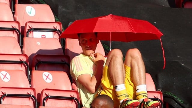 Seine Zeit beim FC Arsenal geht dem Ende zu: Mesut Özil sucht Schutz vor der Sonne unter einem roten Schirm. Seine Zeit beim FC Arsenal geht dem Ende zu: Mesut Özil sucht Schutz vor der Sonne unter einem roten Schirm.