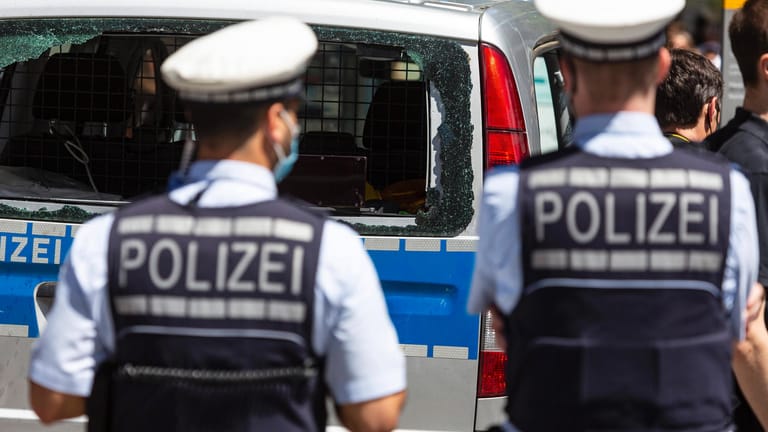 Zwei Polizisten stehen vor einem Polizeiauto mit zerstörter Heckscheibe: Im Nachgang zu der Krawallnacht in Stuttgart kursierte eine Tonaufnahme eines Polizisten.