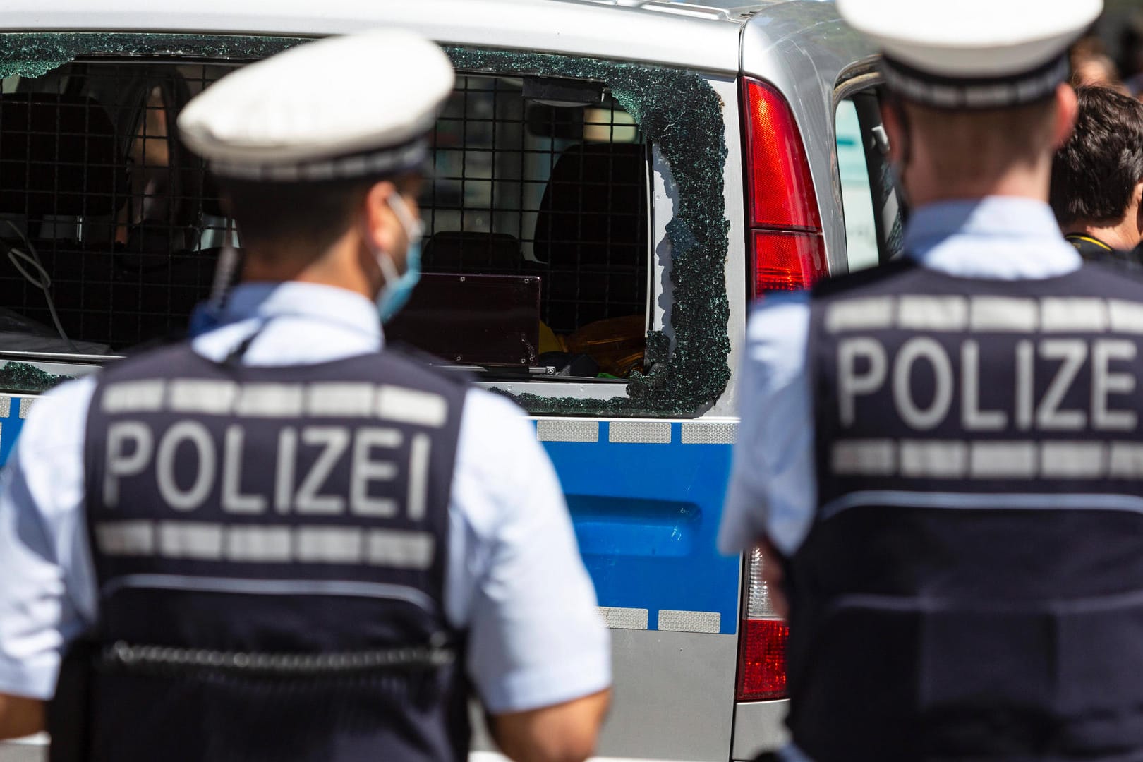 Zwei Polizisten stehen vor einem Polizeiauto mit zerstörter Heckscheibe: Im Nachgang zu der Krawallnacht in Stuttgart kursierte eine Tonaufnahme eines Polizisten.