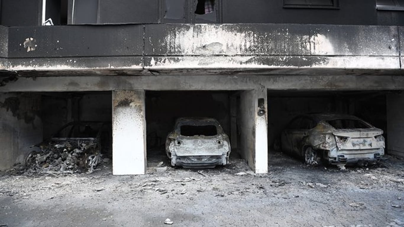 Ausgebrannte Fahrzeuge stehen in der Garage eines Mietshauses in Berlin-Neukölln: Ein Wohnhaus musste infolge des Brandes geräumt werden.