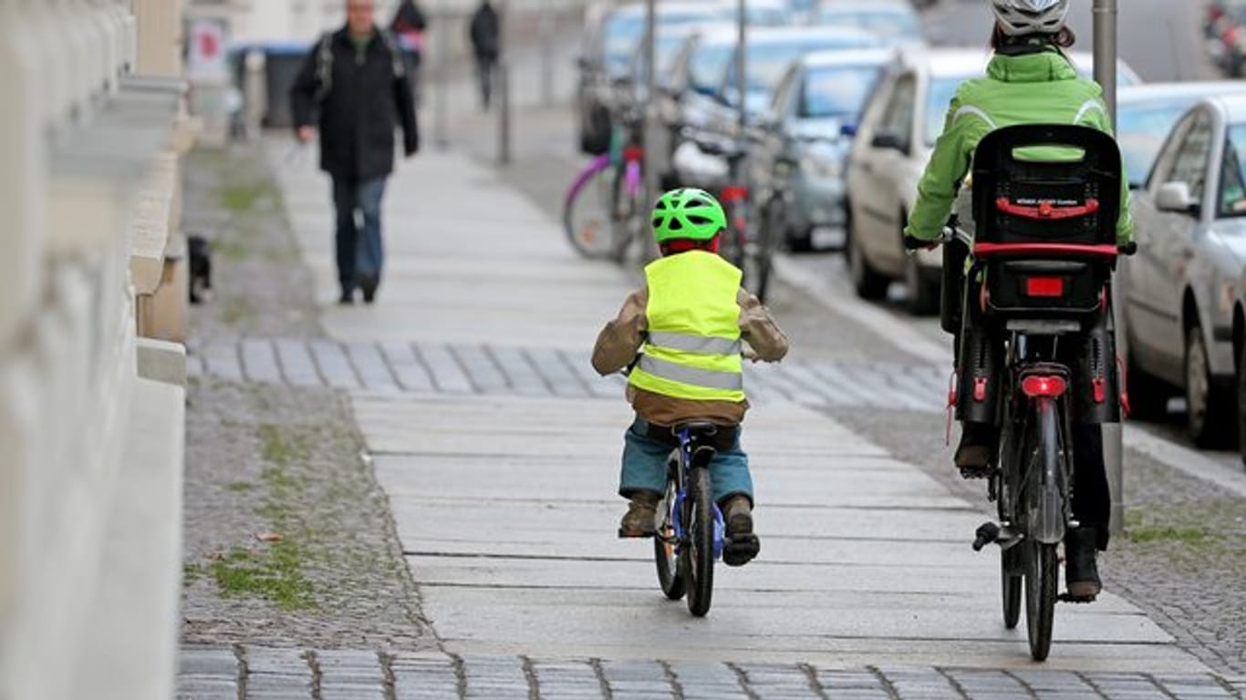 Eine Mutter begleitet ihr Kind auf dem Fahrrad.