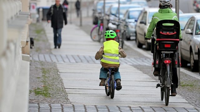 Eine Mutter begleitet ihr Kind auf dem Fahrrad. Eine Mutter begleitet ihr Kind auf dem Fahrrad.